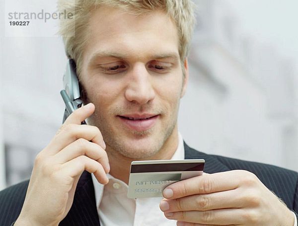 Mann auf dem Handy mit Kreditkarte