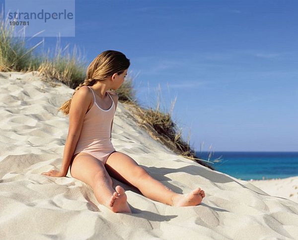 Mädchen auf einer Sanddüne sitzend