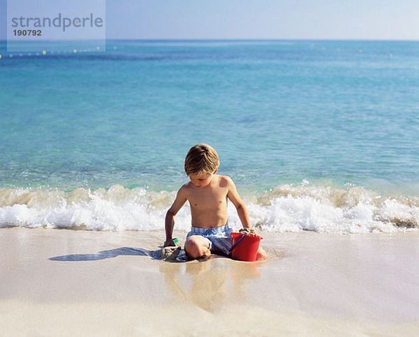 Junge spielt mit nassem Sand