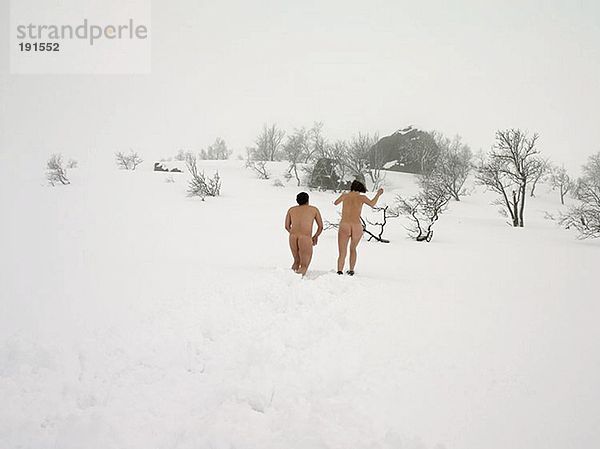 Nacktes Paar  das im Schnee rennt.