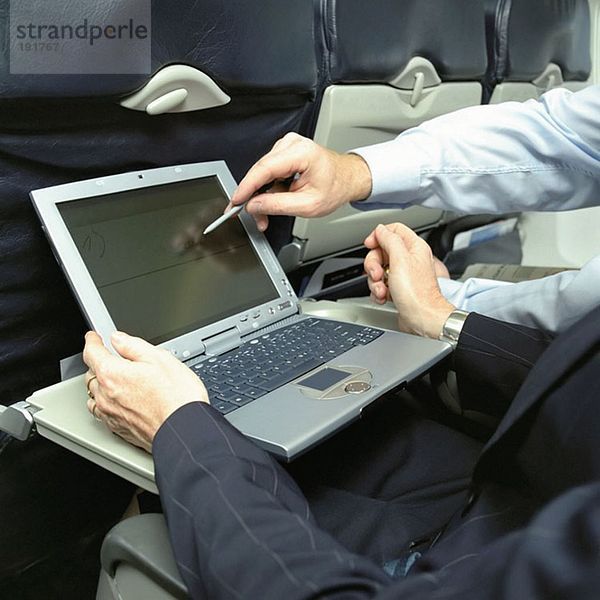 Geschäftsleute mit Laptop im Flugzeug