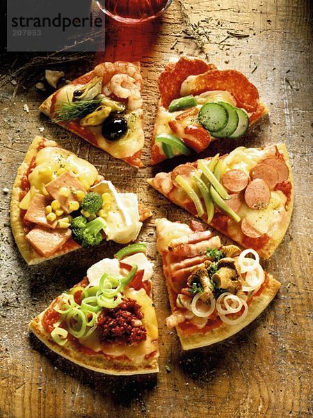 Verschieden belegte Pizzastücke auf Holzuntergrund