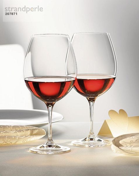 Zwei Rotweingläser auf festlichem Tisch
