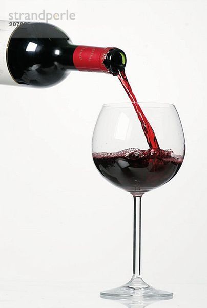 Rotwein aus Flasche in Glas giessen