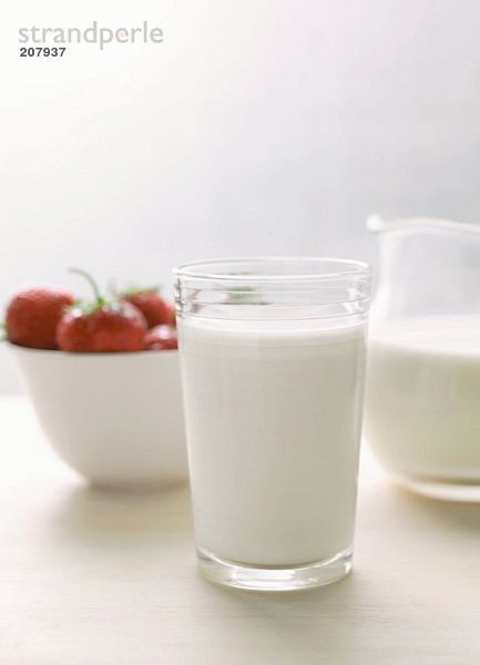 Glas Milch und Milchkrug  Erdbeeren in weisser Schale