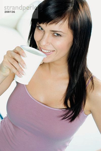 Junge Frau mit einem Becher Trinkjoghurt