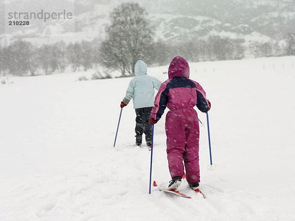 Mädchen auf Skiern wandern durch den Schnee