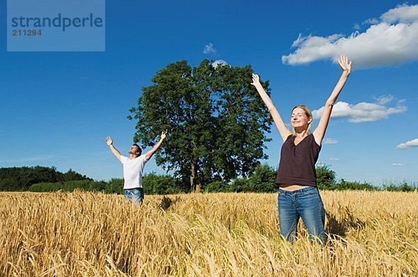 Paar im Feld mit ausgestreckten Armen