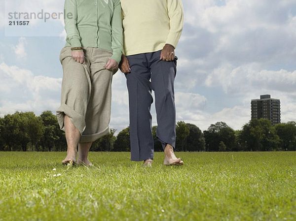Ältere Paare  die barfuß im Park spazieren gehen