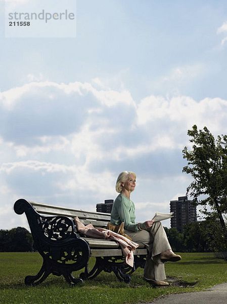 Ältere Frau beim Lesen im Park