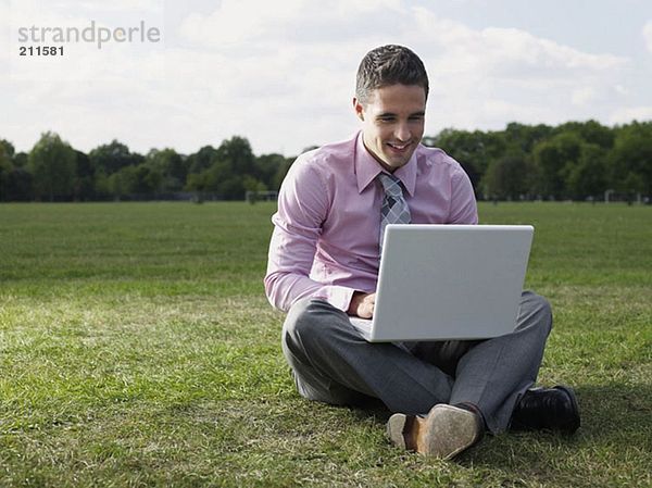 Mann mit einem Laptop im Park