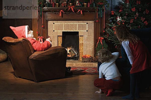 Kinder beobachten den Weihnachtsmann im Wohnzimmer