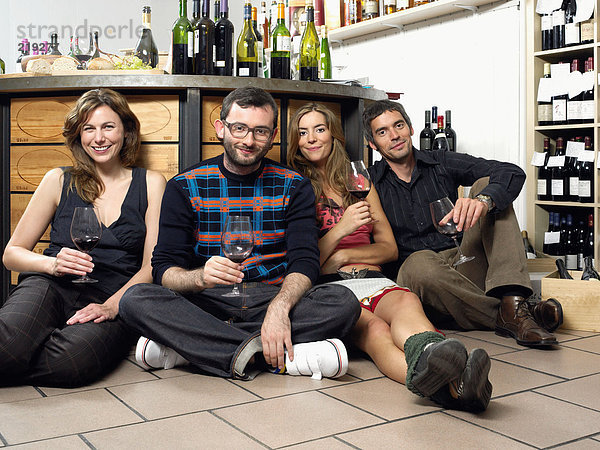 Gruppe von Freunden auf dem Boden bei der Weinprobe