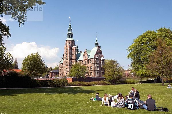 Touristen Ausruhen im Park mit Burg in Hintergrund  Schloss Rosenborg  Kopenhagen  Dänemark