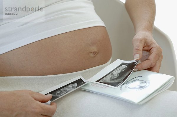 Schwangere Frau beim Betrachten von Ultraschallbildern des Babys  Nahaufnahme