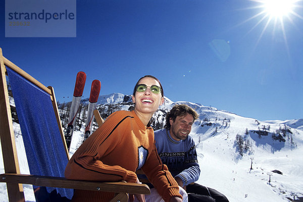Paar entspannt auf dem Liegestuhl in den Alpen  lächelnd