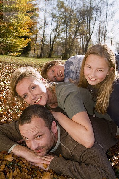 Familie auf Herbstlaub liegend  Portrait
