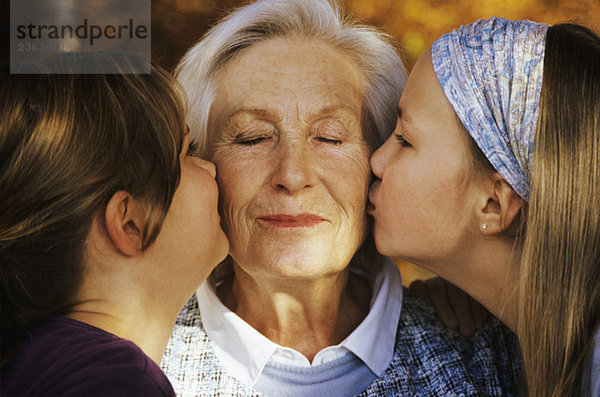 Zwei Mädchen (8-11) küssen Großmutter  Nahaufnahme