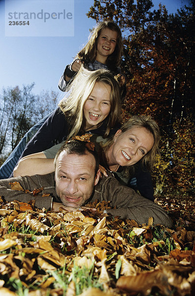 Familie auf Herbstblättern liegend