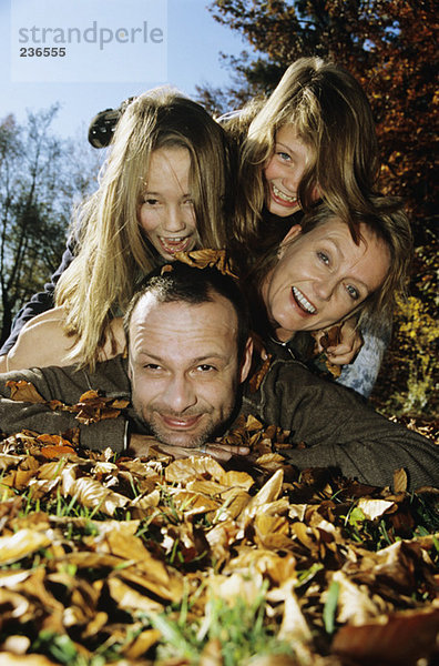 Familie auf Herbstblättern liegend  Nahaufnahme  Portrait