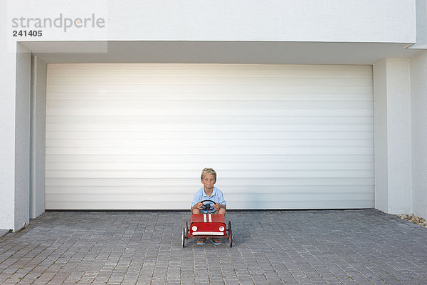 Ein kleiner Junge saß in einem Spielzeugauto.