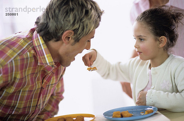 Mädchen füttern Vater mit Fischstäbchen