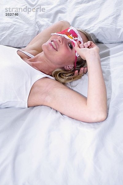 Portrait einer jungen Frau auf Bett liegend und lächelnd