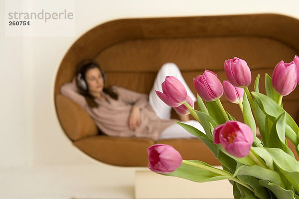 Junge Frau entspannt auf dem Sofa  Fokus auf Tulpen im Vordergrund