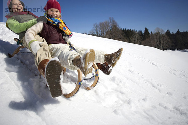 Österreich  Mädchen (6-17) Rodeln auf verschneiter Piste  lächelnd  Tiefblick