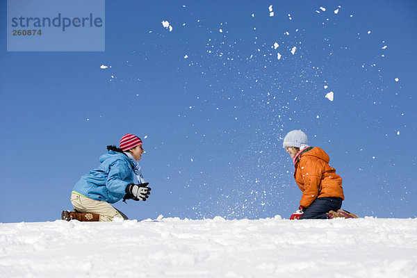 Österreich  Mädchen (12-13) spielen im Schnee  Seitenansicht