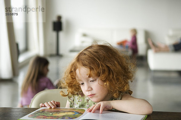 Kleines Mädchen beim Lesen eines Buches  zu Hause