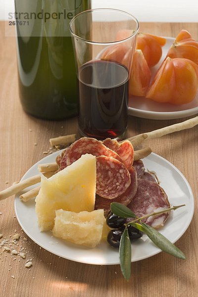 Salami  Käse  Oliven und Grissini auf Teller  Tomaten  Wein