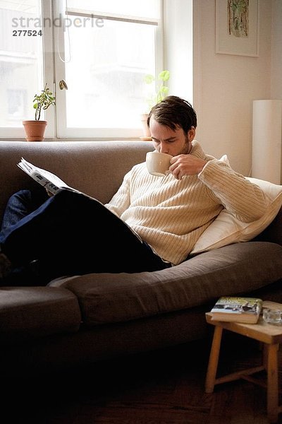 Ein Mann  der in einem Sofa liest.