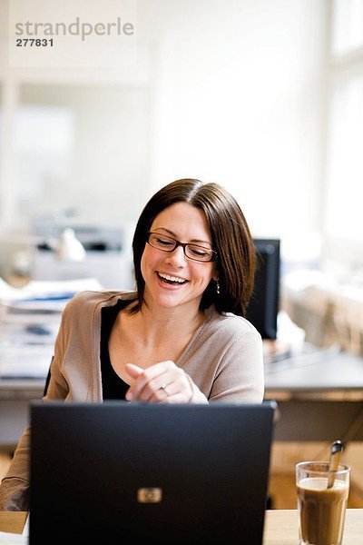 Eine lachend Frau an ihrem Arbeitsplatz.
