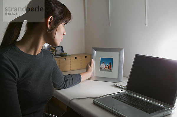 Frau am Schreibtisch beim Betrachten des Fotos