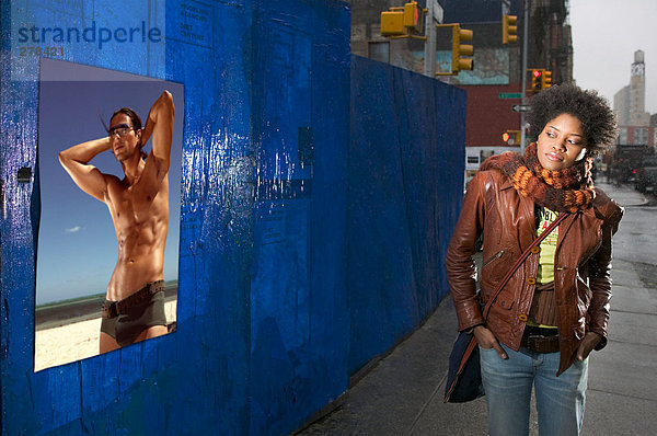 Frau schaut sich das Plakat des nackten Mannes an