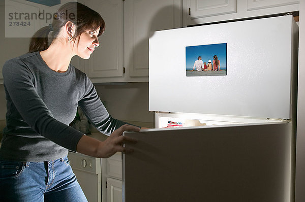 Frau betrachtet Foto auf Kühlschrank