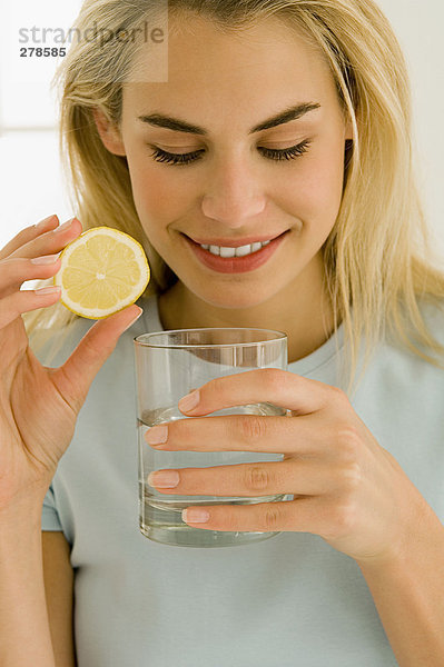 Frau mit Wasserglas und Zitronenscheibe