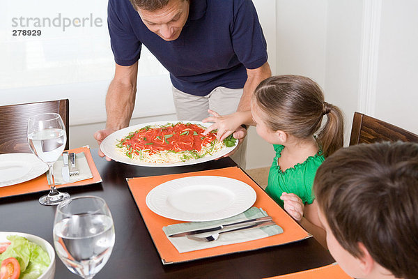 Mädchen  das Spaghetti nimmt  während der Vater versucht  das Essen zu servieren.