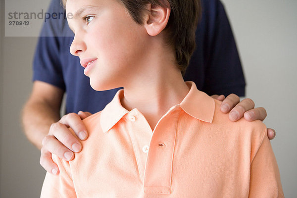 Junge mit Vaters Hand auf den Schultern