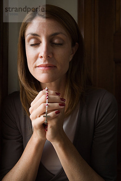 Frau betet mit Rosenkranz
