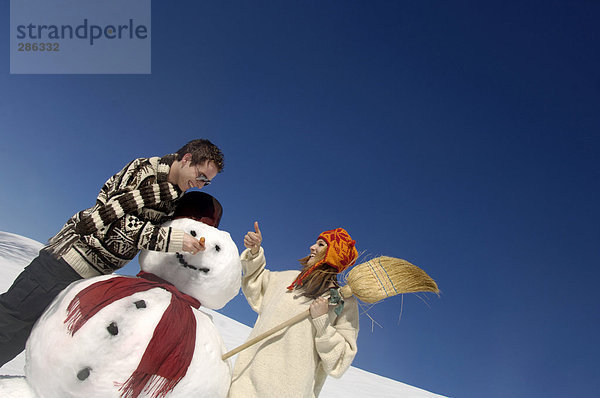 Junges Paar mit Schneemann