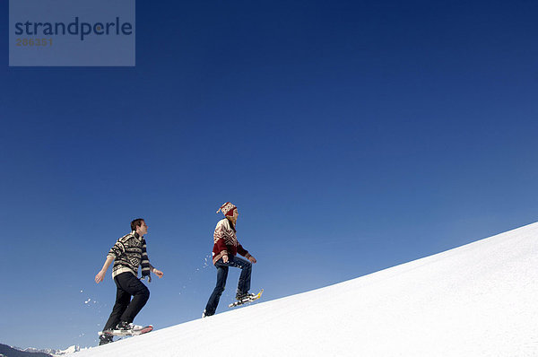 Junges Paar im Schnee  gehende Seitenansicht