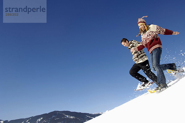 Young couple in snow  running downhill