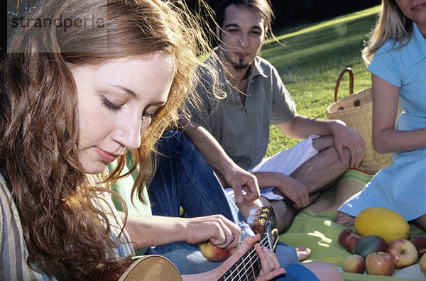 Junge Frau spielt Gitarre für Freunde im Garten  Nahaufnahme