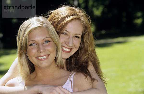 Zwei junge Frauen umarmen sich im Garten  Nahaufnahme  Porträt