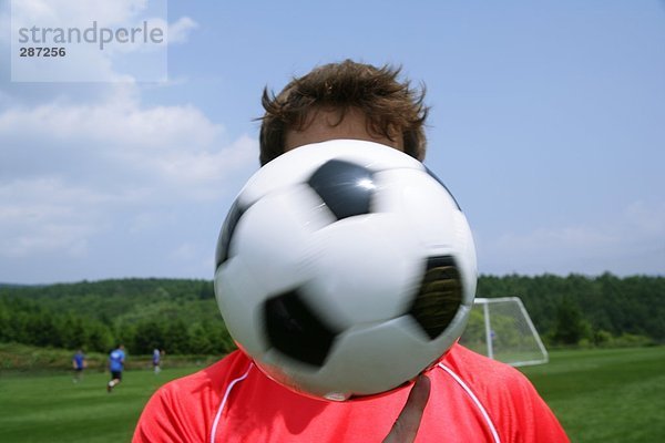 Soccer player's Gesicht verdeckt von ball