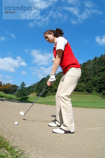 Junge weibliche Golfer nehmen einen Bunkerschlag