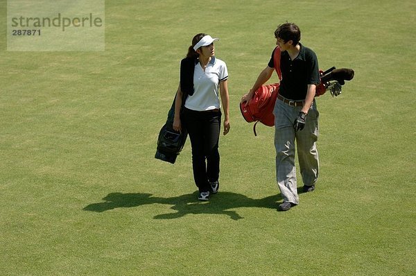 Seitenansicht einer Mann und eine Frau trägt ihre Golfbeutel