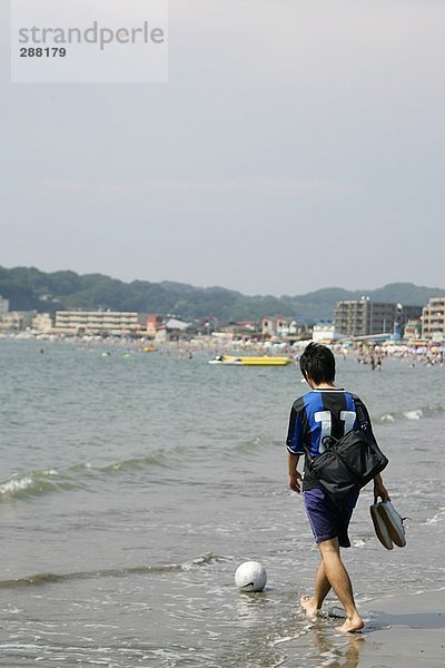 Junge Fußballspieler Wandern am Strand